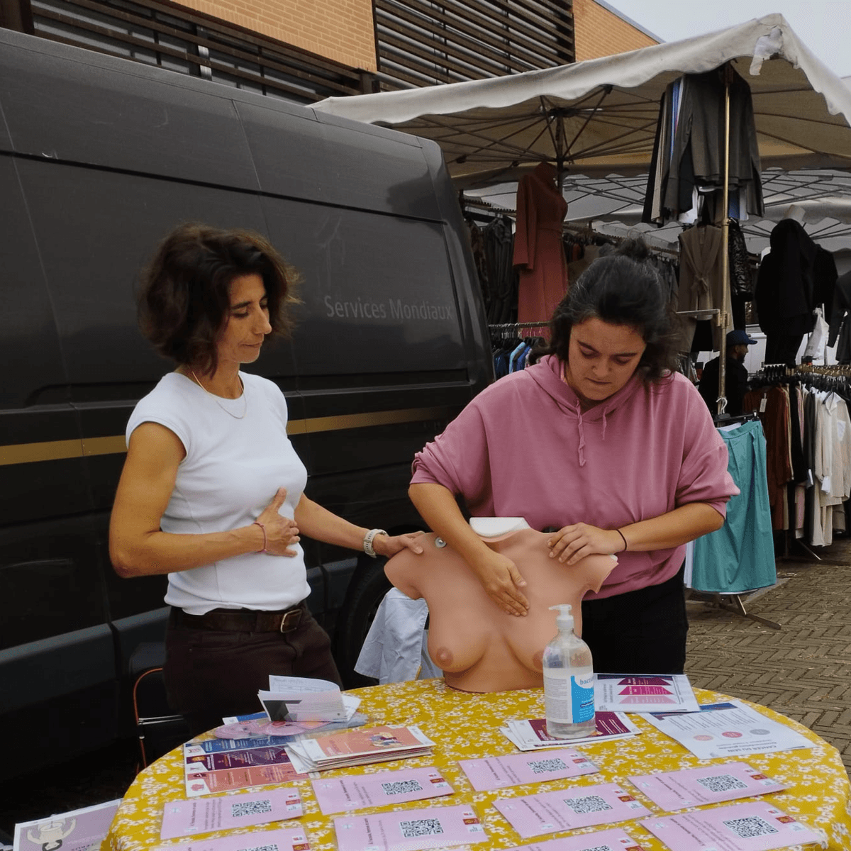 Nous pouvons voir sur la photo, une pharmacienne accompagnant une habitante du quartier en train de s'entraîner à apprendre les bons gestes pour le dépistage du cancer du sein